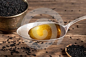 Black cumin seed oil on a spoon and black cumin seeds