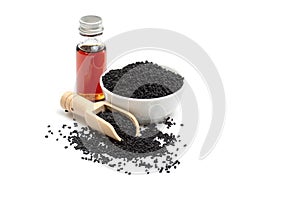 Black cumin seeds in bowl and essential oil in glass bottle.
