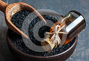 Black cumin seeds in bowl with wooden spoon essential oil