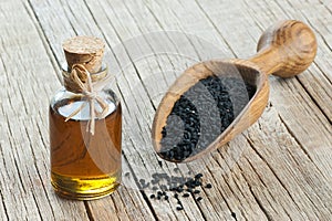 Black cumin seeds and essential oil with bowl and wooden shovel or spoon