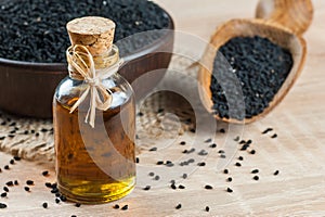 Black cumin seeds and essential oil with bowl and wooden shovel or spoon