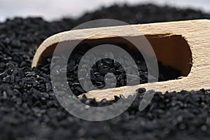 Black cumin seeds and essential oil with bowl and wooden shovel or spoon.