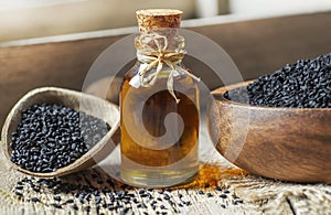 Black cumin seeds essential oil , Nigella Sativa in spoon on wooden background