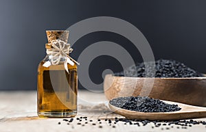Black cumin seeds essential oil , Nigella Sativa in spoon on wooden background photo