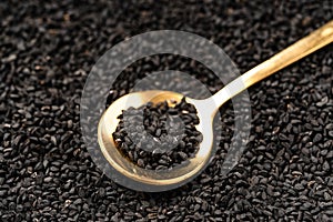 Black cumin seeds on golden spoon macro photography