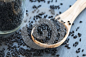 Black cumin seeds on a wooden spoon on gray background