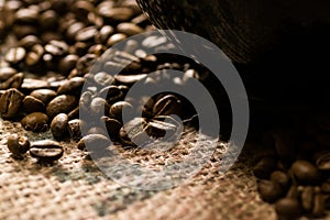 Black cup of on a coffee sack with roasted beans around