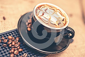 Black cup of freshly brewed espresso coffee. Close-up of coffee cup with milk and beans