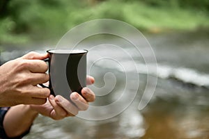 Black cup with hot drinks in male hands