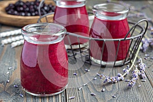 Black currant, greek yogurt, honey and lavender smoothie in jar with berries and flowers on background, horizontal