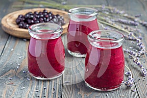 Black currant, greek yogurt, honey and lavender smoothie in jar with berries and flowers on background, horizontal