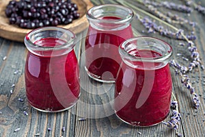 Black currant, greek yogurt, honey and lavender smoothie in jar with berries and flowers on background, horizontal