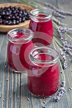 Black currant, greek yogurt, honey and lavender smoothie in jar with berries and flowers on background, vertical