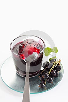 Black currant jam in glass, spoon and black currants