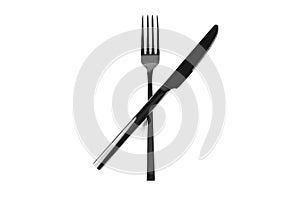 Black cutlery knife and fork crossed on white background