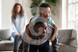 Black dad giving child piggyback ride carrying son on back photo