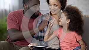 Black daddy giving high five to little curly-haired daughter, family together