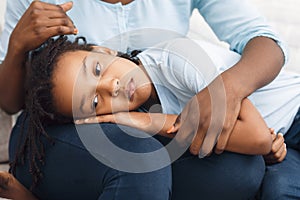 Black daughter lying her head on mom`s lap