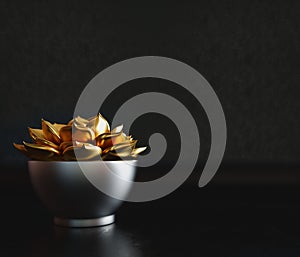 Black decorative pot with gold plant inside on a black background