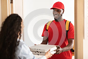 Black delivery man holding and giving pizza boxes