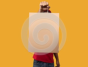 Black delivery man holding paper bag for design