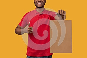 Black delivery man holding paper bag showing thumbs up