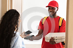 Black delivery man holding pizza box and pos terminal