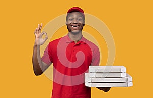 Black delivery man holding pizza boxes, showing okay gesture