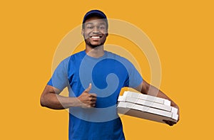 Black delivery man holding pizza boxes, showing thumbs up