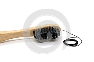 Black dental floss and bamboo toothbrush on a white background.