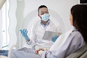 Black Dentist Doctor With Digital Tablet In Hands Consulting Patient In Clinic