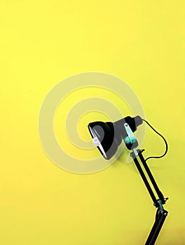 Black desk lamp on yellow empty background