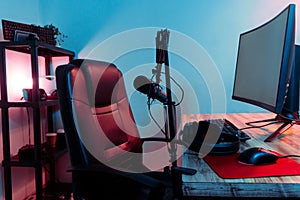 Black desk with a variety of gaming equipment such as keyboards, controllers, and headsets