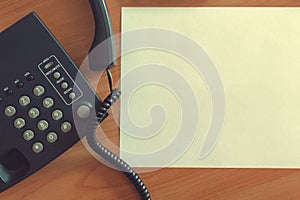 The black desktop telephone on the table.