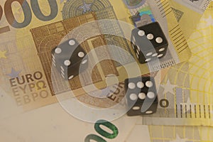 Black dice roll on euro bills.