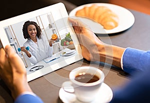 Black dietologist lady consulting patient online via video call on digital tablet