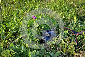 A black digital SLR camera lies on the grass close-up.