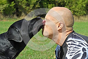 Black dog give kiss man