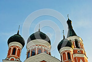 Black domes with crosses on top of painted in red and white orthodox church, The Holy Treasury Saints Temple, bright blue sky