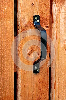 Black door handle on wooden plank door. Architectural details in countrystyle .