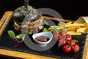 Black double hamburger made from beef, with jalapeno pepper. Tomato sauce in a white sauce.