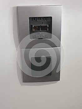 black double switch with gray plastic faceplate, partially damaged.