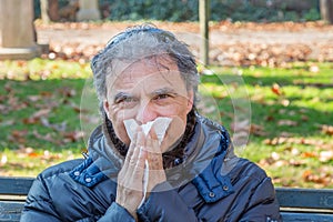 Black down jacket man blowing his nose with tissue