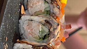 BLACK DRAGON ROLL Crabmeat, Avocado, Kappa Inside with Unagi, Avocado, Fish Flakes and Fish slow motion from the side