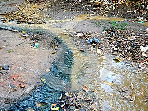 Black drain water and yellow muddy soil water flowing
