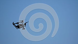 Black drone quadcopter with camera flying over blue sky. Black drone in the sky. Flying quadrocopter drone in the sky