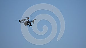 Black drone quadcopter with camera flying over blue sky. Black drone in the sky. Flying quadrocopter drone in the sky