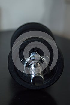 Black dumbbell on black table with warm light tone.