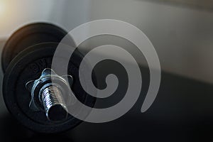 Black dumbbell on black table with warm light tone.