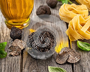 Black edible winter truffle, tagliatelle and fresh basil on wooden table. The most popular cooking ingredients